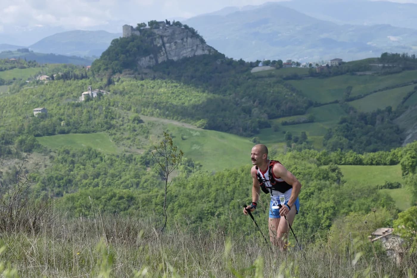 Un atleta sui sentieri con la rupe di Canossa sullo sfondo
